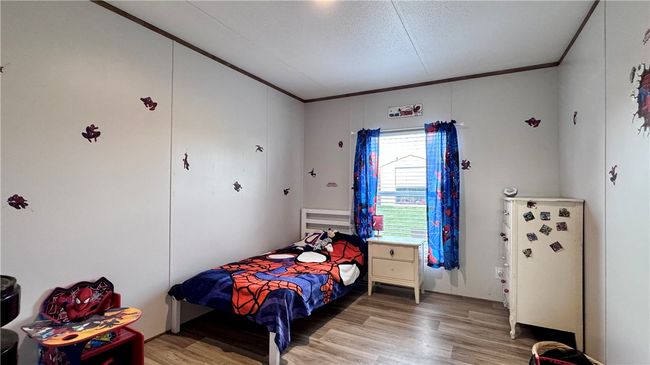 Bedroom with light wood-style flooring, crown molding, and a textured ceiling | Image 20