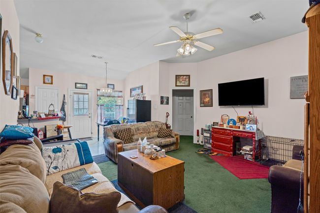 Carpeted living room featuring a ceiling fan and a chandelier | Image 7