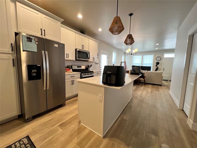 Kitchen featuring stainless steel appliances, light countertops, white cabinetry, light wood-style floors, and recessed lighting | Image 10