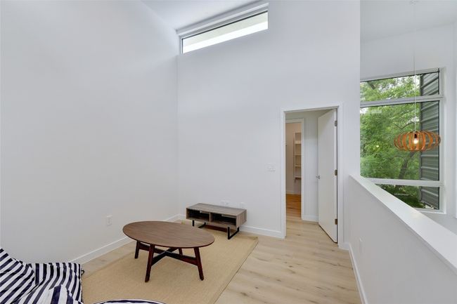 Living area with light wood-style flooring, a high ceiling, and baseboards | Image 19