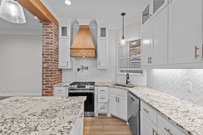 Kitchen with crown molding, light wood-style floors, appliances with stainless steel finishes, white cabinets, and glass insert cabinets | Image 9