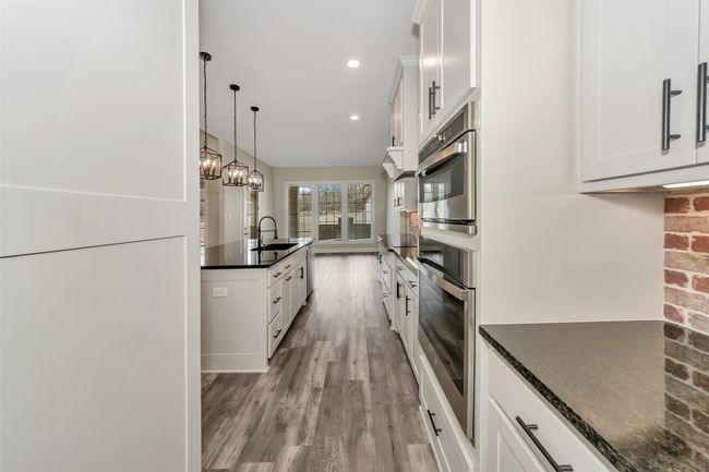 Kitchen with oven, light wood-type flooring, recessed lighting, white cabinetry, and a sink | Image 6