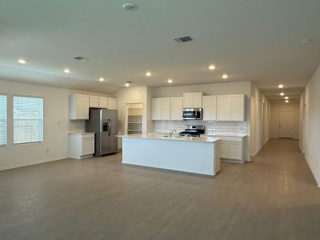 Kitchen featuring stainless steel appliances, a sink, decorative backsplash, white cabinetry, and recessed lighting | Image 21