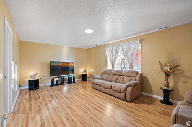 Living room featuring a textured ceiling and light wood-type flooring | Image 28