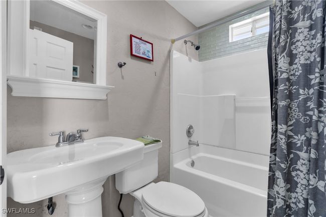 Bathroom featuring a sink, shower / bathtub combination with curtain, and toilet | Image 23