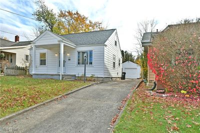 View of property exterior featuring a garage, an outbuilding, and a lawn | Image 2