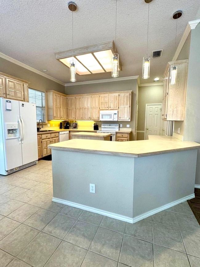 Kitchen featuring crown molding, white appliances, visible vents, and a textured ceiling | Image 7
