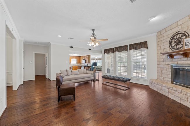 Living room featuring wood finished floors, crown molding, baseboards, and a ceiling fan | Image 8