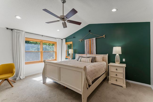 Upstairs, the primary suite offers a peaceful retreat designed with both comfort and style in mind. Vaulted ceilings and a ceiling fan enhance the airy atmosphere, while dual 5x5 walk-in closets with built-ins provide ample storage and convenience. | Image 13