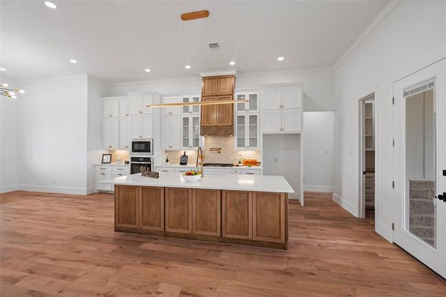 This kitchen features a spacious island, elegant cabinetry, and modern appliances, perfect for both culinary creations and gathering with loved ones. | Image 17