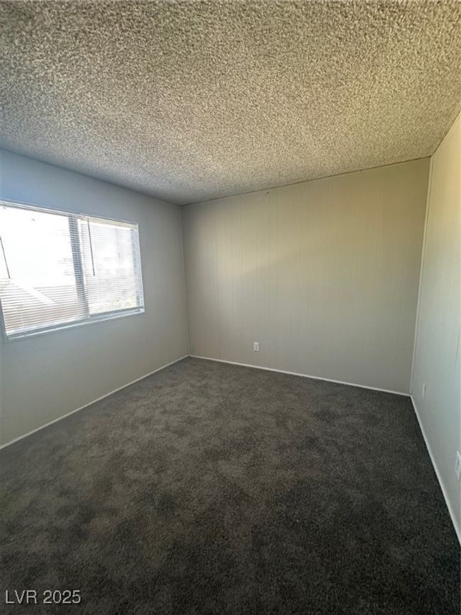 Empty room with dark carpet and a textured ceiling | Image 15