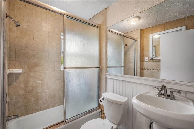 Unit #70 Full bathroom with enclosed tub / shower combo, a textured ceiling, toilet, and sink | Image 33