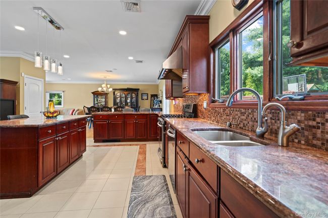 Kitchen featuring crown molding, dark stone counters, pendant lighting, backsplash, and light tile patterned flooring | Image 9