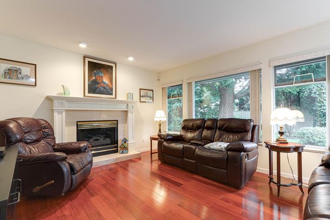 Living area with wood-type flooring, a fireplace, and baseboards | Image 17