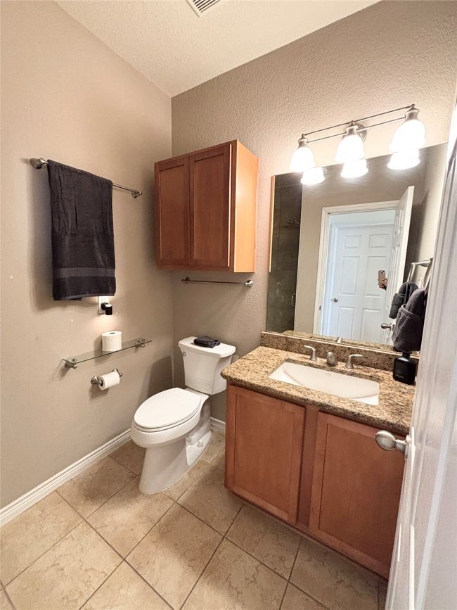 Bathroom featuring toilet, vanity, a textured ceiling, baseboards, and tile patterned floors | Image 10