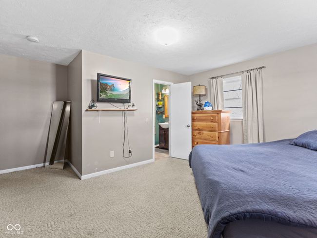carpeted bedroom featuring ensuite bathroom, baseboards, and a textured ceiling | Image 19