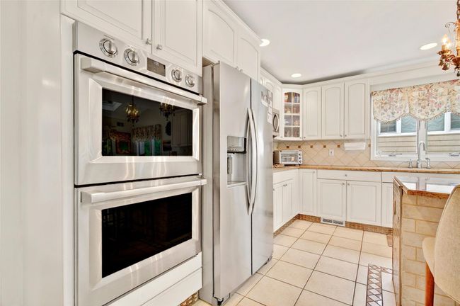 Kitchen with appliances with stainless steel finishes, a sink, light tile patterned floors, glass insert cabinets, and white cabinetry | Image 19