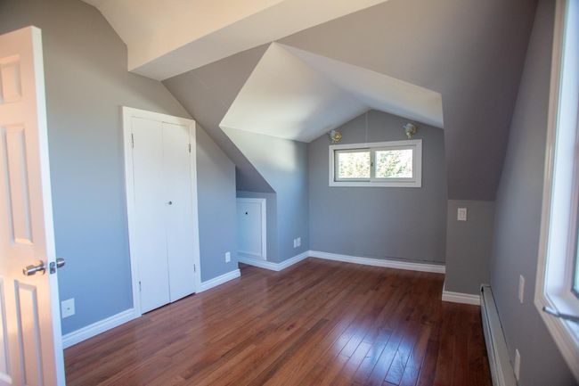 Additional living space featuring dark wood-type flooring, a baseboard radiator, and lofted ceiling | Image 20