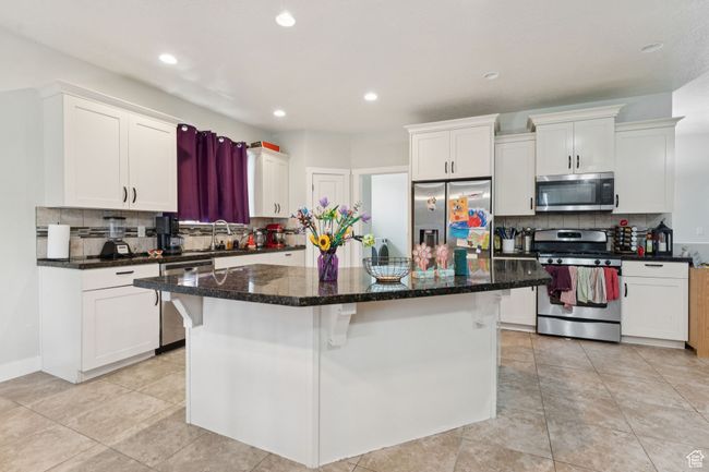 Kitchen with appliances with stainless steel finishes, decorative backsplash, white cabinets, and recessed lighting | Image 6
