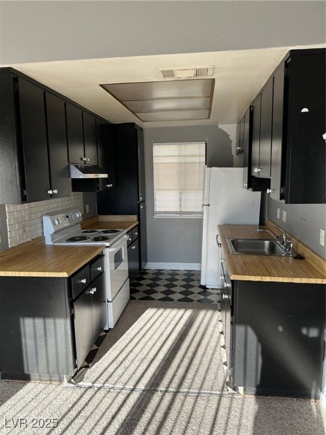 Kitchen with dark cabinetry, stove, and tile patterned floors | Image 4