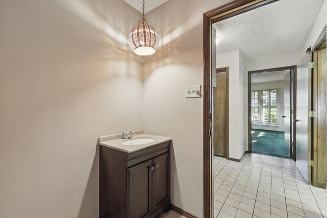 Bathroom with tile patterned floors, a textured ceiling, baseboards, a notable chandelier, and vanity | Image 13