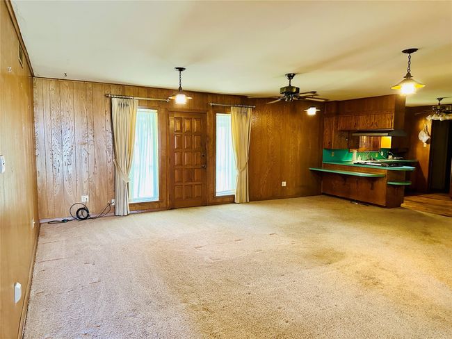 Kitchen featuring pendant lighting, carpet, a peninsula, and wood walls | Image 8