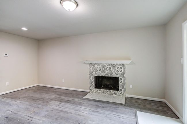 A stylish fireplace with decorative tile and neutral walls, complemented by dark wood flooring. Ideal for a cozy living space. | Image 5