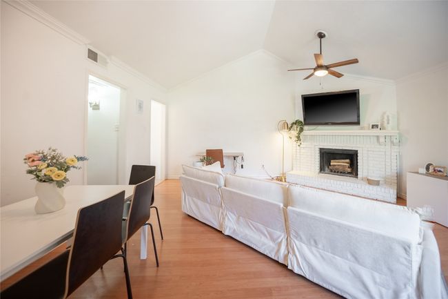 Living room with light wood-type flooring, visible vents, lofted ceiling, a ceiling fan, and ornamental molding | Image 12