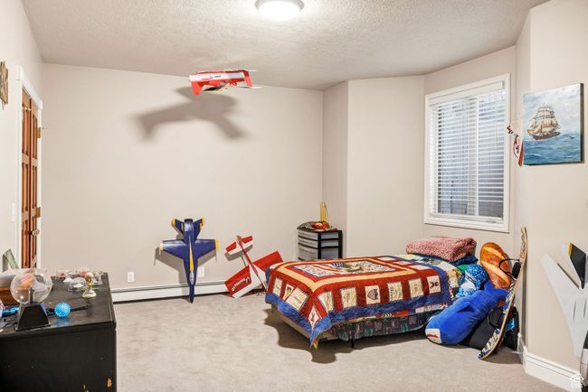 Bedroom with baseboard heating, carpet, and a textured ceiling | Image 63