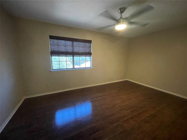 Empty room with dark wood-type flooring, baseboards, and a ceiling fan | Image 17