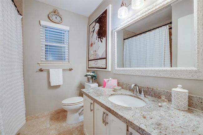 Primary Bathroom, painted cabinetry, updated hardware, updated light fixture, a shower/tub combo with floor-to-ceiling tiling & travertine tiled floor | Image 21