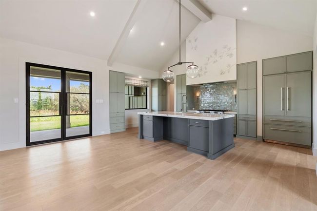 The kitchen is the heart of this home and it anchors the great room so well. Beautiful selections add warmth and elegance to the space. Walk out the beautiful steel doors to the outdoor entertaining area. | Image 5