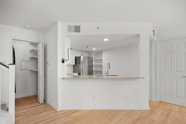 Kitchen featuring freestanding refrigerator, a sink, light wood-type flooring, a peninsula, and white cabinets | Image 9