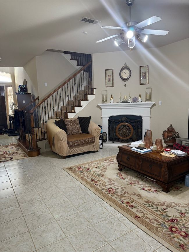 Living room featuring stairs, a ceiling fan, a fireplace, and tile patterned flooring | Image 15
