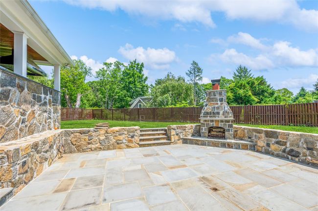 Fenced backyard featuring an outdoor stone fireplace and a patio area | Image 20