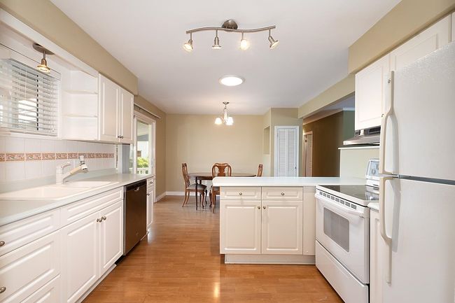 Kitchen featuring white appliances, white cabinetry, and a peninsula | Image 10