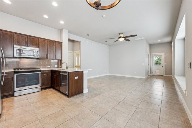 Kitchen featuring appliances with stainless steel finishes, a sink, a peninsula, light countertops, and decorative backsplash | Image 7