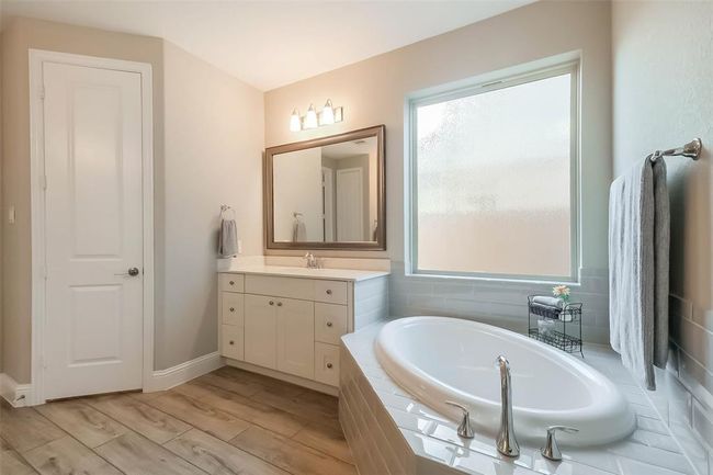 The primary bathroom is equipped with separate bathroom vanities with QUARTZ COUNTERS, large soaking tub under a frosted glass window and large walk-in shower. | Image 8