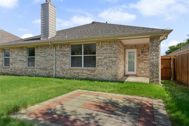 Rear view of house featuring a chimney, a patio area, brick siding, and roof with shingles | Image 26