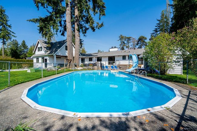 View of swimming pool with a lawn, a fenced in pool, a water slide, and fence | Image 24