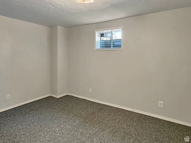 Empty room with dark carpet, baseboards, and a textured ceiling | Image 25