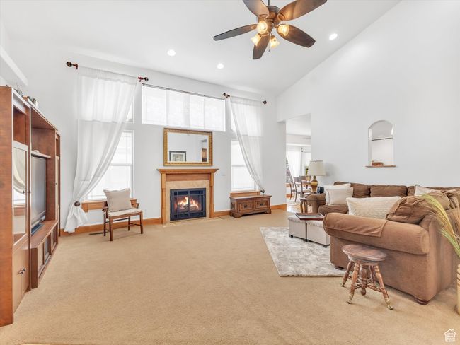 Carpeted living room with recessed lighting, a high ceiling, baseboards, a fireplace, and ceiling fan | Image 7