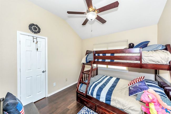Bedroom featuring wood finished floors, lofted ceiling, baseboards, and a ceiling fan | Image 15