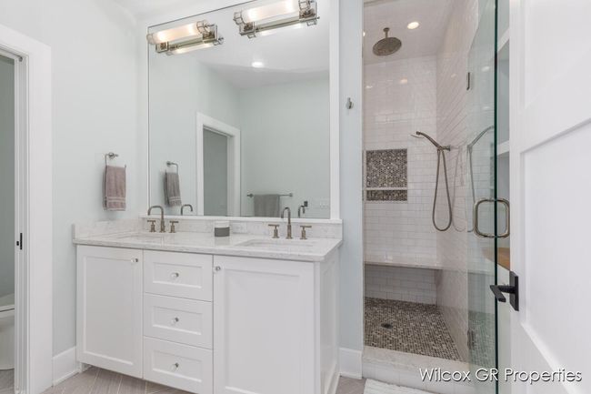 Lovely primary bath includes dual quartz vanity, custom tile shower and floors. | Image 26