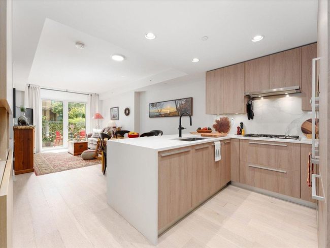 Kitchen with light brown cabinets, open floor plan, a peninsula, light wood-type flooring, and recessed lighting | Image 12