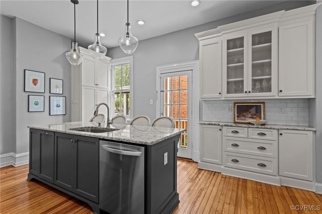 Kitchen featuring stainless steel dishwasher, white cabinetry, a sink, and light wood finished floors | Image 12