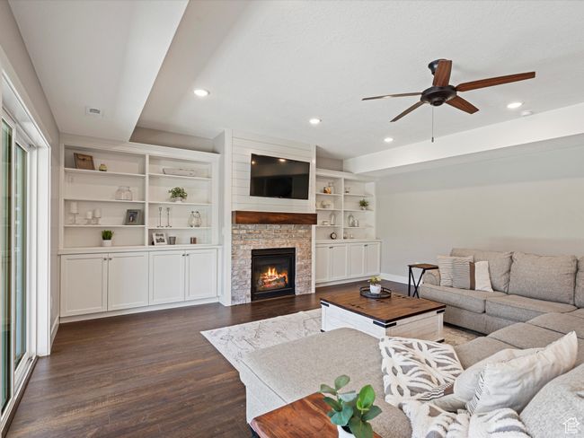 Living room with a ceiling fan, dark wood-style floors, recessed lighting, baseboards, and a glass covered fireplace | Image 5