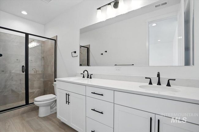 Full bath with double vanity, a stall shower, wood finished floors, and recessed lighting | Image 21