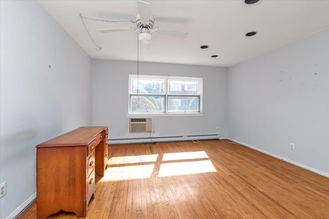 Bedroom featuring baseboards, a baseboard radiator, ceiling fan, light wood-type flooring, and a wall mounted AC | Image 16