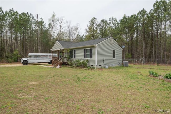 View of front of house featuring a wooden deck, cooling unit, fence, a front lawn, and crawl space | Image 31